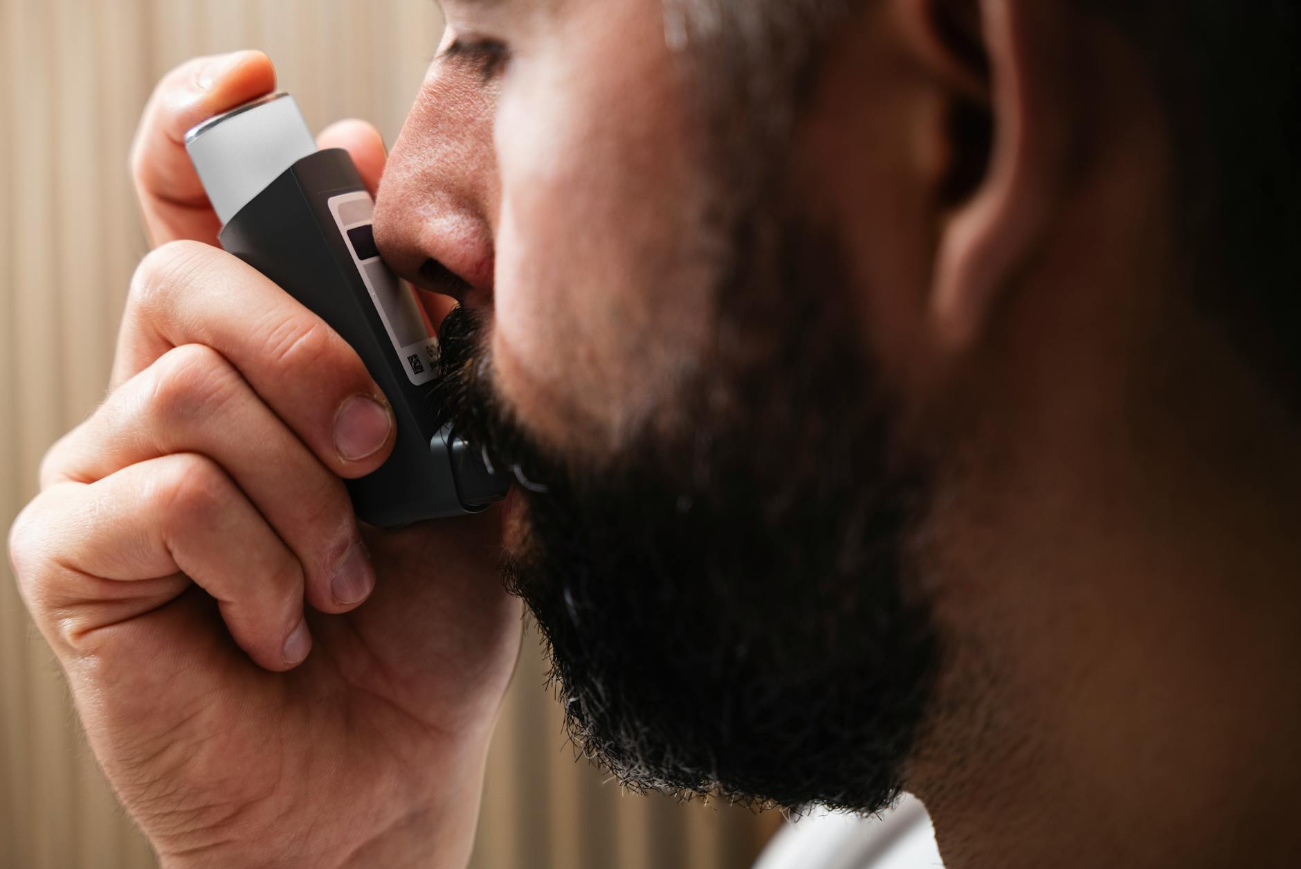 close up of man using inhaler for asthma relief